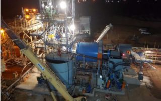 A mining factory with equipment above the ground lit up at night