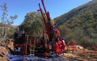 Workers climbing up a red machine standing in a gorge