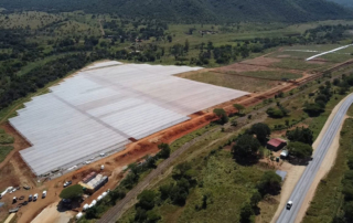 A bird's eye view shot of a covered mining area with greenery and hills surrounding it
