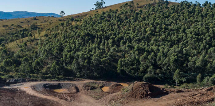 Rolling green hills and trees behind a mining site.