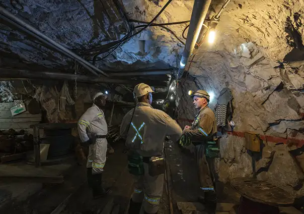 Image of three people standing and talking to each other inside a mine