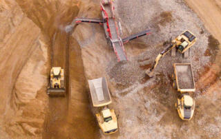 A bird’s eye view of machinery digging in sand to excavate a mine site.